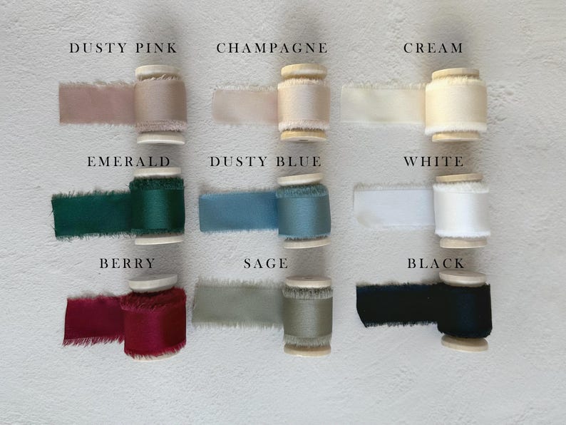 May include: Nine spools of frayed-edge ribbon arranged in a grid, labeled with colors: Dusty Pink, Champagne, Cream, Emerald, Dusty Blue, White, Berry, Sage, and Black. Each spool features a smooth, solid-colored fabric ribbon with raw, textured edges.