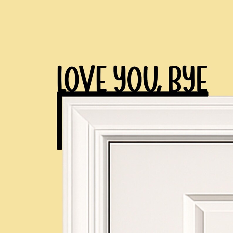 Black wood L-shaped door-corner signs reading “LOVE YOU, BYE” in bold letters. The Small version measures 10-3/4" wide × 6" tall, and the Large version measures 17-1/4" wide × 7-3/8" tall. Both are 1/4" thick and designed to perch on a door-frame corner without installation hardware.