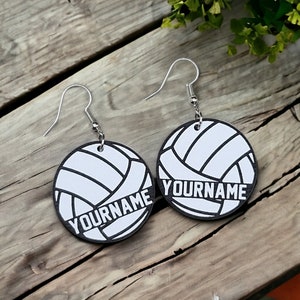 May include: A pair of black and white volleyball earrings with the text "YOURNAME" on each earring.