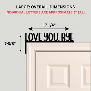 Black wood L-shaped door-corner signs reading “LOVE YOU, BYE” in bold letters. The Small version measures 10-3/4" wide × 6" tall, and the Large version measures 17-1/4" wide × 7-3/8" tall. Both are 1/4" thick and designed to perch on a door-frame corner without installation hardware.