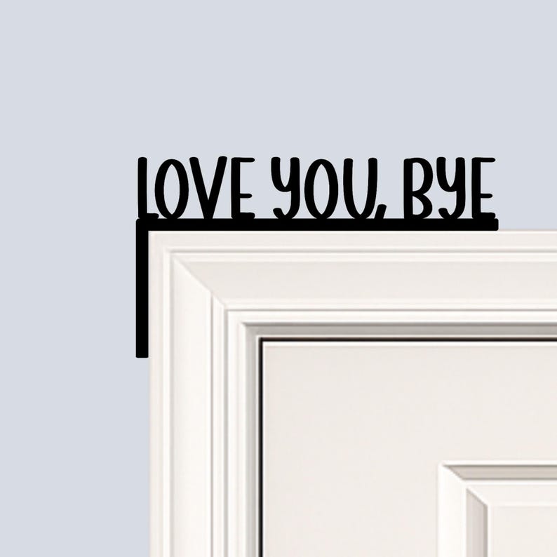 Black wood L-shaped door-corner signs reading “LOVE YOU, BYE” in bold letters. The Small version measures 10-3/4" wide × 6" tall, and the Large version measures 17-1/4" wide × 7-3/8" tall. Both are 1/4" thick and designed to perch on a door-frame corner without installation hardware.