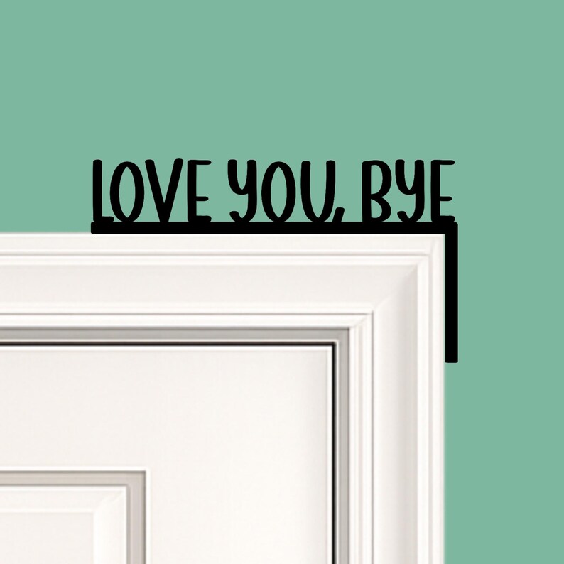 Black wood L-shaped door-corner signs reading “LOVE YOU, BYE” in bold letters. The Small version measures 10-3/4" wide × 6" tall, and the Large version measures 17-1/4" wide × 7-3/8" tall. Both are 1/4" thick and designed to perch on a door-frame corner without installation hardware.