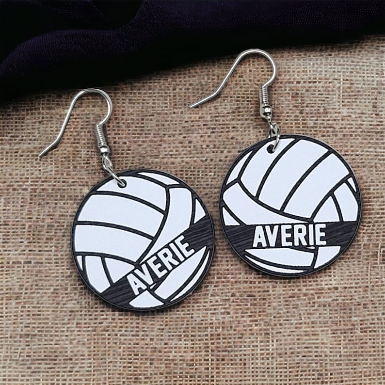 May include: A pair of silver earrings with a white volleyball design and the name "Averie" printed on each earring.