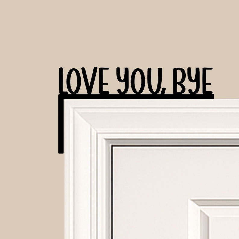 Black wood L-shaped door-corner signs reading “LOVE YOU, BYE” in bold letters. The Small version measures 10-3/4" wide × 6" tall, and the Large version measures 17-1/4" wide × 7-3/8" tall. Both are 1/4" thick and designed to perch on a door-frame corner without installation hardware.