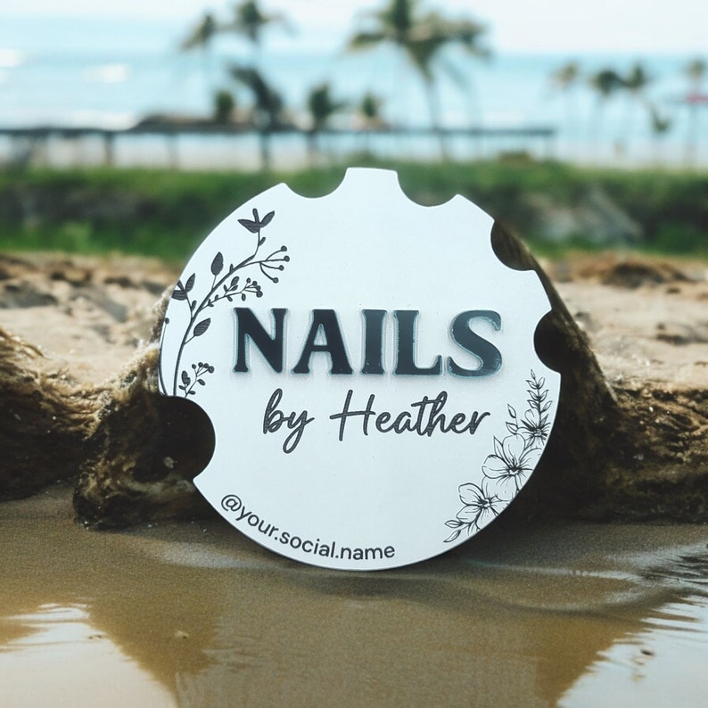 May include: White round sign with black floral designs and the text "NAILS by Heather @your.social.name"