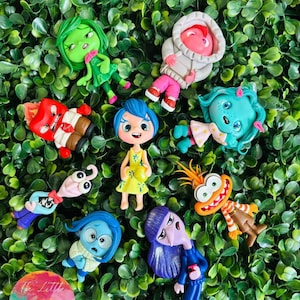 May include: A set of nine colorful clay figurines inspired by the characters from the movie Inside Out. The characters include Joy, Sadness, Anger, Fear, Disgust, Bing Bong, and others. The figurines are all hand-painted and have a whimsical, cartoonish style. @THE LITTLE CLAY SHOP