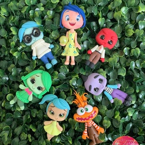 May include: Set of eight hand-painted clay figurines inspired by the characters from the movie Inside Out. The characters include Joy, Sadness, Anger, Disgust, Fear, Bing Bong, and two additional characters. The figurines are all approximately 2 inches tall and are painted in bright, vibrant colors.