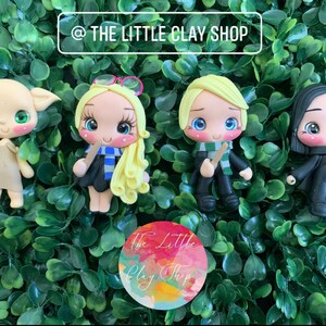 Puede incluir: Cuatro figuritas de arcilla hechas a mano de personajes de la serie Harry Potter. Las figuritas son de Dobby, Hermione Granger, Harry Potter y Draco Malfoy. Las figuritas llevan todas su uniforme escolar de Hogwarts y sostienen varitas.