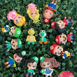 Puede incluir: Una colección de 15 figuras de arcilla polimérica hechas a mano de personajes de la franquicia de videojuegos Super Mario Bros. Las figuras están pintadas en varios colores, incluyendo rojo, verde, azul, amarillo y marrón. Los personajes incluyen a Mario, Luigi, la princesa Peach, Toad, Bowser y Yoshi.