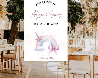 May include: A white welcome sign on a wooden easel, with the text "Welcome to Alysa & Sam's Baby Shower." The sign features a watercolor illustration of a rainbow, unicorn, and bow. The date 05.22.20xx is printed at the bottom.