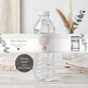 May include: A clear plastic water bottle with a custom label featuring a pink hot air balloon illustration, eucalyptus sprigs, and text reading Megan's Baby Shower, Thank you for coming and showering our baby with love, and Baby Shower Nutrition Facts.