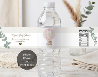 May include: A clear plastic water bottle with a custom label featuring a pink hot air balloon illustration, eucalyptus sprigs, and text reading Megan's Baby Shower, Thank you for coming and showering our baby with love, and Baby Shower Nutrition Facts.
