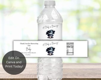 Könnte beinhalten: Klare Plastikwasserflasche mit einem weißen Etikett mit der Aufschrift "A Baby is Brewing!" und einer Grafik eines Kessels. Ein Banner darunter lautet "Thank You for Showering Our Baby". Die Flasche steht auf einer Holzoberfläche.