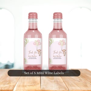 May include: Set of eight mini wine bottle labels with a pink and white design featuring a monkey holding balloons. The labels say "Thank You" and "Sam's Baby Shower".