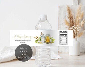 May include: A clear plastic water bottle with a white label featuring the text A Baby is Brewing, Ashley & Jay's Baby Shower, 11.5.20xx, and a Baby Shower Nutrition Facts table. The label includes watercolor illustrations of a baby bottle and beer mug.