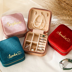 a set of three jewelry cases sitting on top of a bed