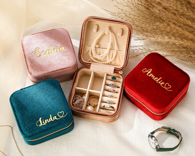 a set of three jewelry cases sitting on top of a bed