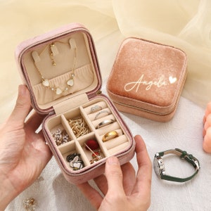 a person holding a pink case filled with jewelry