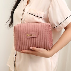 a woman holding a pink purse with a name on it