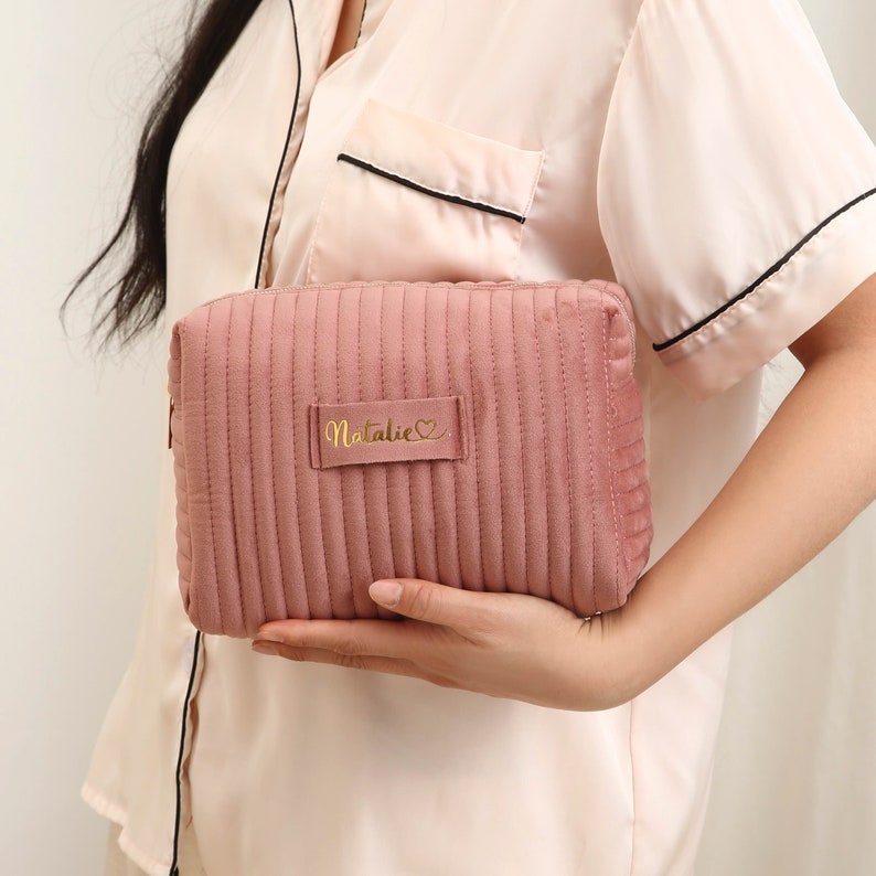 a woman holding a pink purse with a name on it