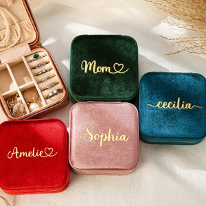 four personalized jewelry cases sitting on a bed