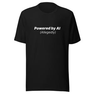 Könnte beinhalten: Schwarzes T-Shirt mit dem weißen Text "Powered by AI (Allegedly)". Das T-Shirt hat kurze Ärmel und einen Rundhalsausschnitt.