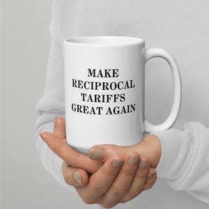 Könnte beinhalten: Eine weiße Keramik-Kaffeetasse mit schwarzem Text, der "MAKE RECIPROCAL TARIFFS GREAT AGAIN" lautet.