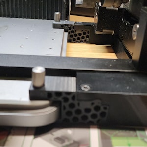 Könnte beinhalten: Nahaufnahme einer schwarz-grauen Maschine mit rotem Knopf. Die Maschine hat eine Reihe von Lüftungsschlitzen und eine graue Plattform. Das Bild konzentriert sich auf die mechanischen Komponenten und ihr kompliziertes Design.