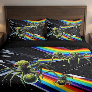 May include: Black bedding set featuring a vibrant design of green alien-like creatures with red eyes, set against a backdrop of a rainbow and a starry night sky. Includes two pillowcases and a duvet cover.