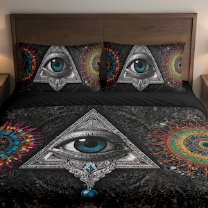 May include: Black bedding set featuring a large eye within a triangle, with a blue iris, and decorative patterns. The set includes a duvet cover and two pillowcases. The design has a mystical theme with colorful circular patterns.