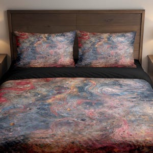 May include: A bed with a duvet cover and two pillowcases. The bedding features a swirling abstract design in shades of red, blue, and gold against a black sheet. The headboard is made of dark wood.