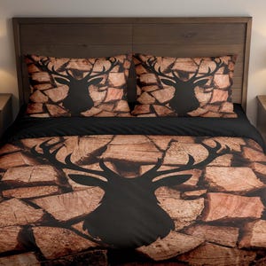 Könnte beinhalten: Ein Bett mit einem dunkelbraunen Holz-Kopfteil, zwei Nachttischen und einem Teppich. Die Bettwäsche zeigt eine schwarze Hirschsilhouette auf einem Holzmaserungshintergrund. Zwei passende Kissenbezüge sind sichtbar. Die Tagesdecke hat ein schwarzes oberes Bettlaken.
