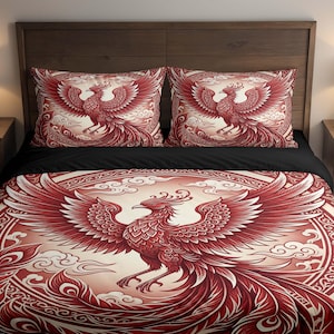 May include: A red and cream-colored bedding set featuring a phoenix design. The set includes a duvet cover and two pillowcases. The phoenix is depicted with outstretched wings and intricate details. The bedding is on a wooden bed frame.