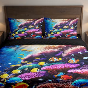 Könnte beinhalten: Bettwäsche-Set mit Unterwassermotiv. Die Bettdecke und Kissenbezüge zeigen eine farbenfrohe Szene mit Fischen, Korallen und Wasserpflanzen. Das Design umfasst Blau-, Gelb-, Rot- und Lilatöne und schafft eine lebendige Unterwasserwelt.