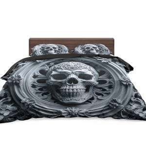 May include: A bed with a dark wooden headboard and a skull-themed bedding set. The duvet cover and pillowcases feature a detailed skull design in shades of gray and black, creating a gothic aesthetic.