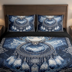 May include: A blue and white bedding set featuring a deer head, dreamcatcher, and mountain scene. The set includes a duvet cover and two pillowcases. The design incorporates feathers and geometric patterns, creating a nature-inspired theme.