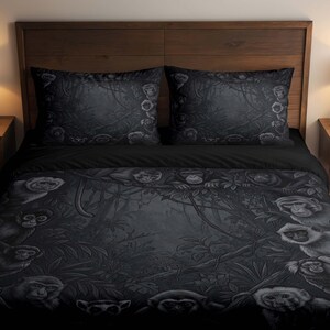 May include: A black and dark gray bedding set featuring a duvet cover and two pillowcases decorated with a detailed monochromatic jungle scene. The pattern displays multiple monkeys nestled among dense tropical foliage and tangled tree branches.