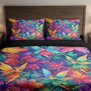 May include: A colorful bedding set featuring a vibrant floral and fairy design. The comforter and two pillowcases showcase fairies with colorful wings amidst large flowers in shades of purple, orange, and blue.