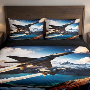 Puede incluir: Juego de cama con una imagen dramática de aviones de combate volando sobre un lago de montaña. El juego incluye una funda nórdica y dos fundas de almohada. Los aviones son de color gris oscuro con detalles amarillos, sobre un cielo azul y montañas nevadas.