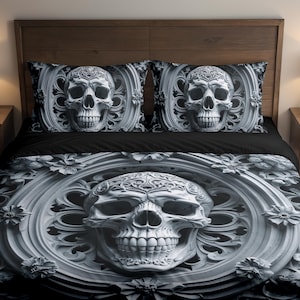May include: A black and white skull-themed bedding set. The duvet cover and two pillowcases feature a detailed skull design within an ornate frame. The skull has intricate details, and the overall aesthetic is gothic.