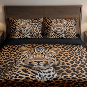 Könnte beinhalten: Ein Bett mit einer Bettdecke mit Leopardenmuster und zwei passenden Kissenbezügen. Die Bettdecke und die Kissenbezüge zeigen ein Nahaufnahmebild des Gesichts eines Leoparden. Das Bett hat ein schwarzes Laken und steht vor einem hölzernen Kopfteil.