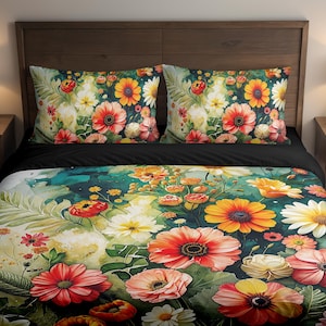 May include: Floral bedding set featuring a vibrant watercolor design. The set includes a duvet cover and two pillowcases adorned with large, colorful flowers in shades of red, orange, yellow, and white against a dark background. The bed is made up with a black sheet.