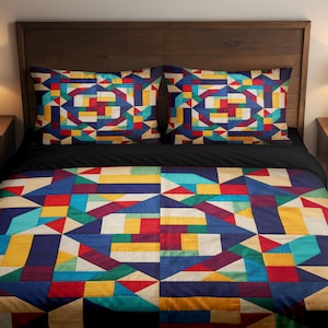 Può includere: Un set da letto composto da una trapunta e due federe con un motivo geometrico formato da forme rettangolari e triangolari multicolori nelle tonalità del blu, rosso, giallo, verde acqua e crema, su una base di colore nero tinta unita.
