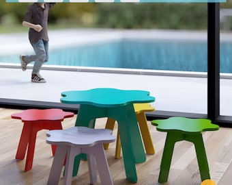 May include: A set of four cloud-shaped children's furniture in teal, red, purple, and green. The table and three stools are made of wood and have a simple, modern design.