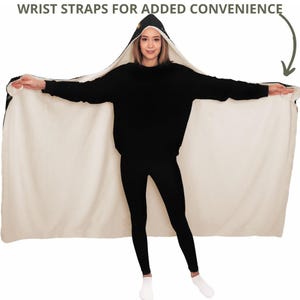 Puede incluir: Una manta negra con capucha y forro de borreguillo blanco. La manta tiene correas para las mu&ntilde;ecas para mayor comodidad. La modelo lleva la manta como una bata.