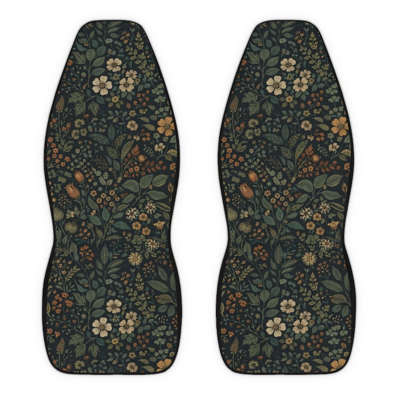 May include: Two car seat covers with a dark background and a floral pattern. The pattern includes various flowers and leaves in shades of cream, orange, and green. The covers have a black border and a contoured shape.