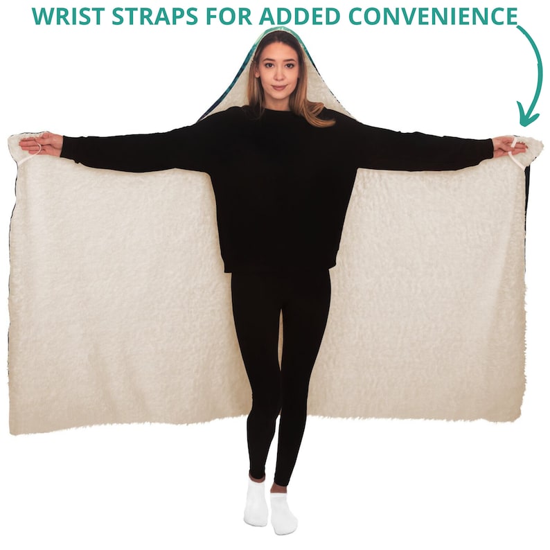 May include: A hooded blanket with a cream-colored, fluffy interior and a dark blue and patterned exterior. The blanket has wrist straps for added convenience. The person in the image is wearing black clothing.