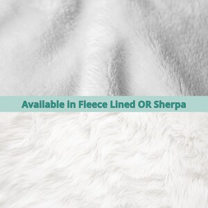 May include: Close-up of two white, fluffy textures. The top texture is a fleece-like material, while the bottom is a longer, shaggier sherpa fabric. Text across the middle reads "Available in Fleece Lined OR Sherpa."