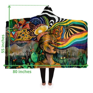 May include: Hooded blanket with a vibrant, psychedelic design. The artwork features a woman's face with a rainbow emanating from her eye, set against a desert landscape. The blanket measures 80 inches wide and 55 inches high.