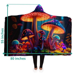May include: Hooded blanket featuring a vibrant illustration of glowing mushrooms in a forest setting. The blanket measures 55 inches high and 80 inches wide. The design includes orange, blue, purple, and green colors, creating a whimsical and colorful aesthetic.